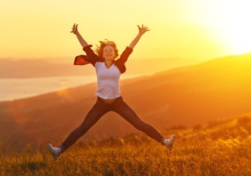 Happy woman jumping and enjoying life  at sunset in mountains